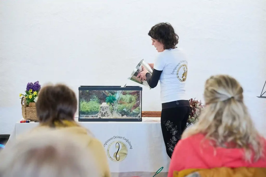 Eine Frau gießt Wasser aus einem Eimer in ein Aquarium während des Workshops